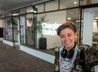 Student takes a selfie style photo outside the neon Charging Station sign at Hawthorn campus, The Junction.