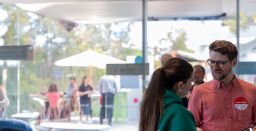 Two people smiling and talking to each other, right of frame.