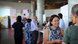 A woman in a blue dress speaks to a Swinburne academic at the Swinburne Study Expo.