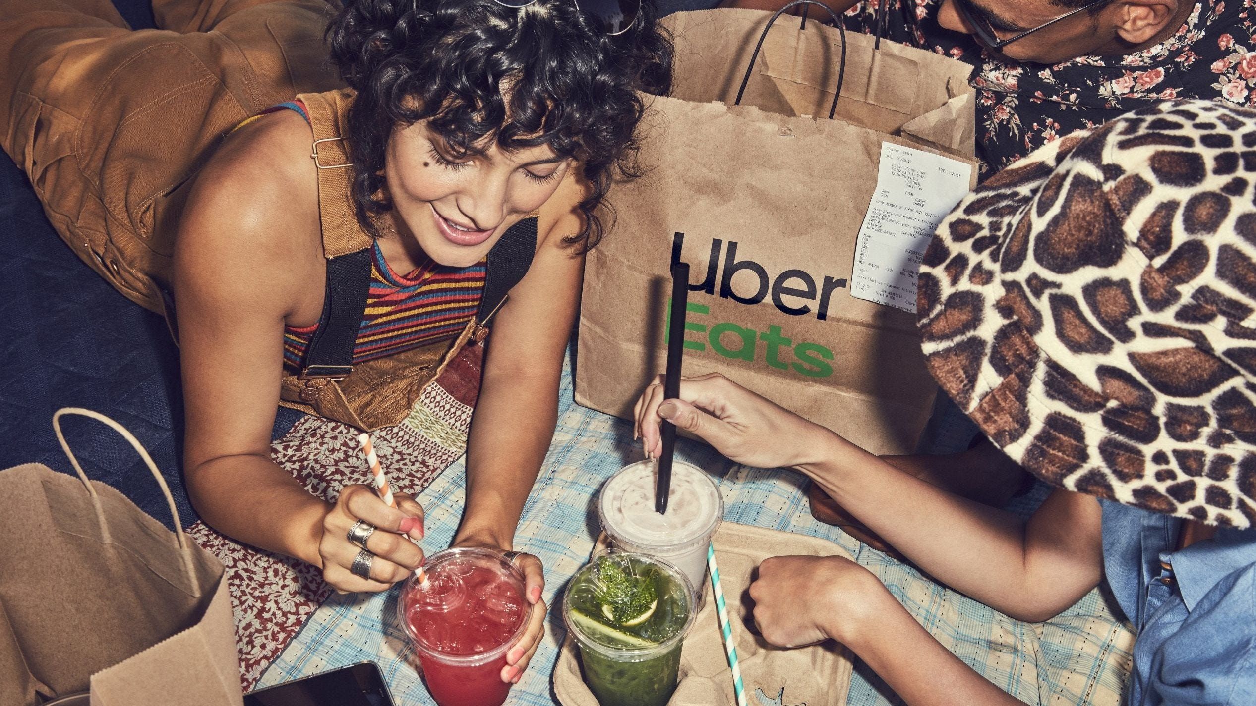 Two people pushing straws into their drinks ordered from Uber Eats 