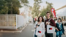 Two people standing with tote bags smiling at the camera