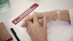 A close-up shot of the hands of a Community Services student during a counselling session with a client with form and pen on a desk