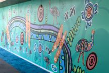 Indigenous artwork by Mandi Barton, featuring emus, bright colours and flowing lines along a wall. 