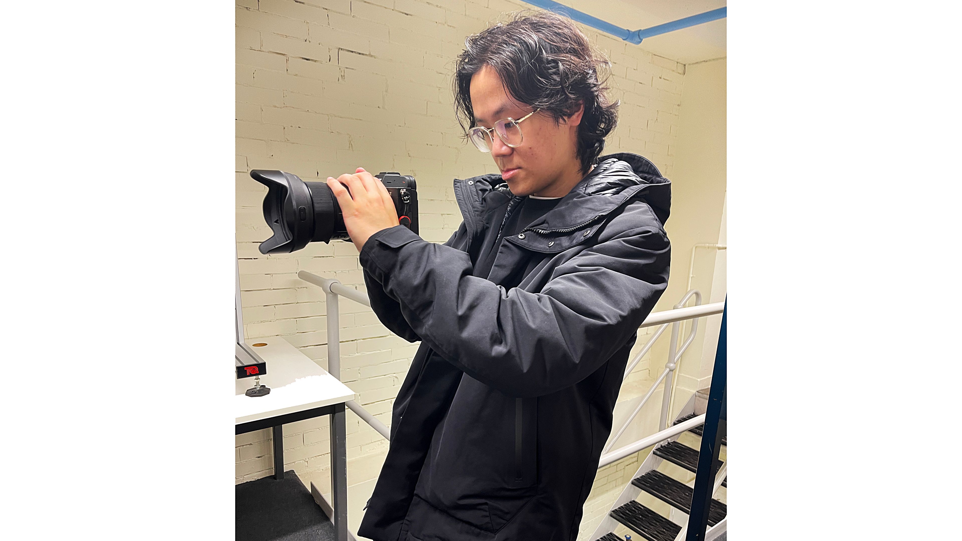 A student looks into a camera as he takes a photo