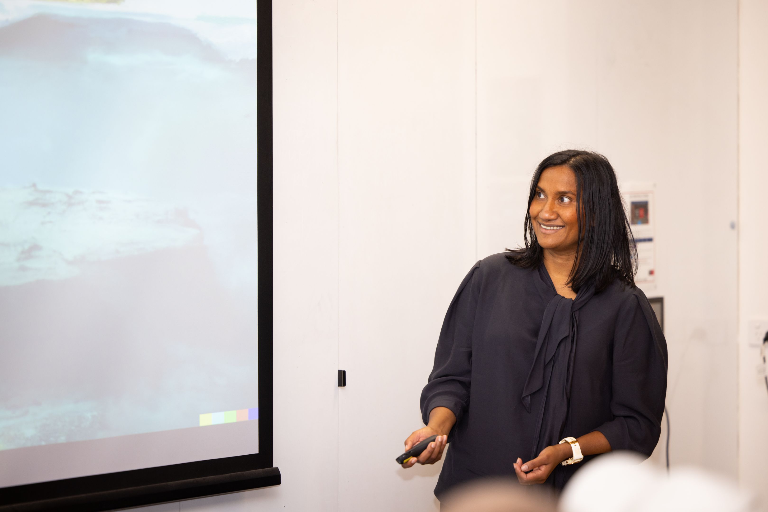 Mariyam Sayers presenting in front of a projector and smiling at the Pre-accelerator Pitch night.