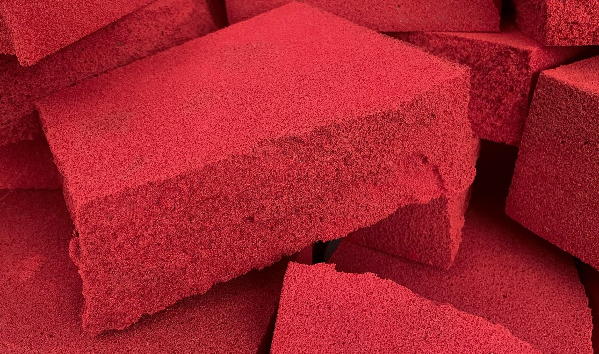Large rectangular chunks of red foam are piled on top of one another