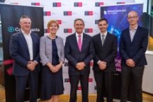 Grant Dooley, Professor Pascale Quester, The Hon John Brumby AO, Dr Werner van der Merwe and Professor Chris Vale stand in front of branded banners for ColdQuanta, Swinburne and Breakthrough Victoria