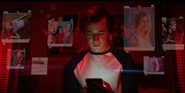 A still from the Netflix documentary The Social Dilemma with a young male looking at his smart phone