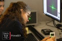 Young woman sitting in front of a computer, using equipment.