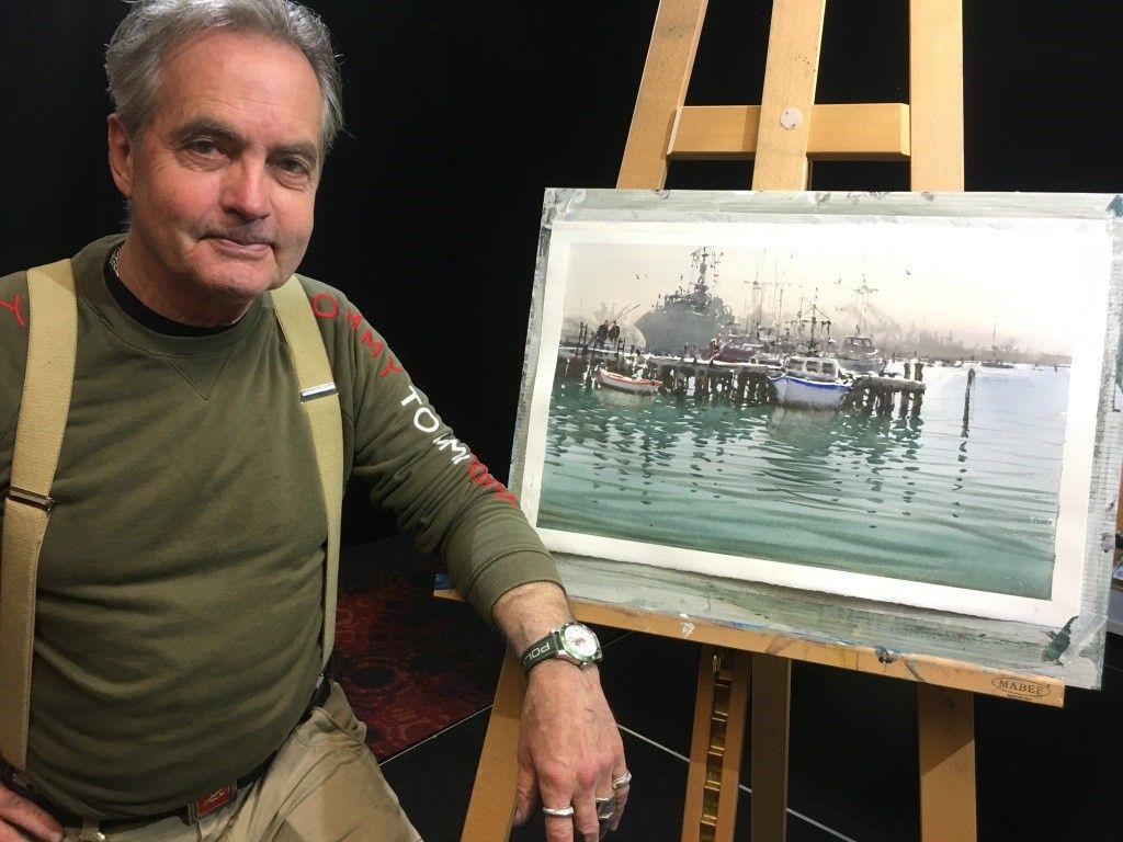 Joseph Zbukvic showing his painting of boat on the sea