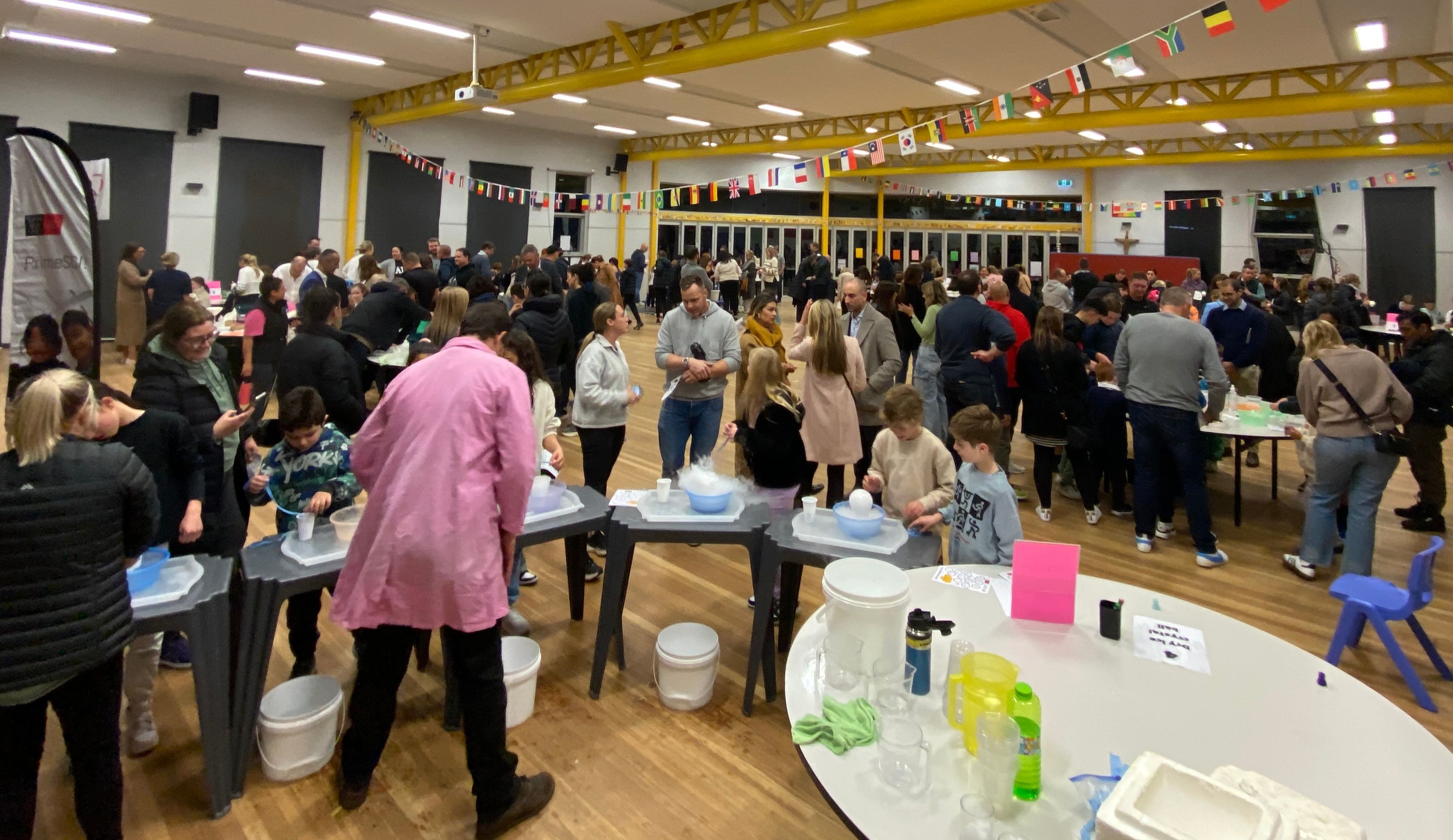 Group of people in a hall speaking and looking at science equipment and experiments