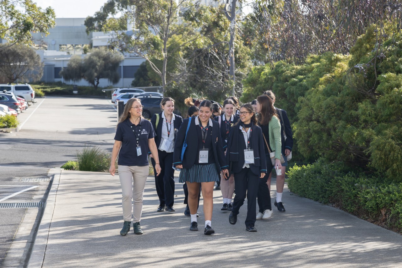 high school girls walking together on a footpath in a carpark.