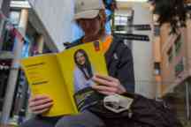 Student wearing a cap outside reads the Undergraduate Course guide book