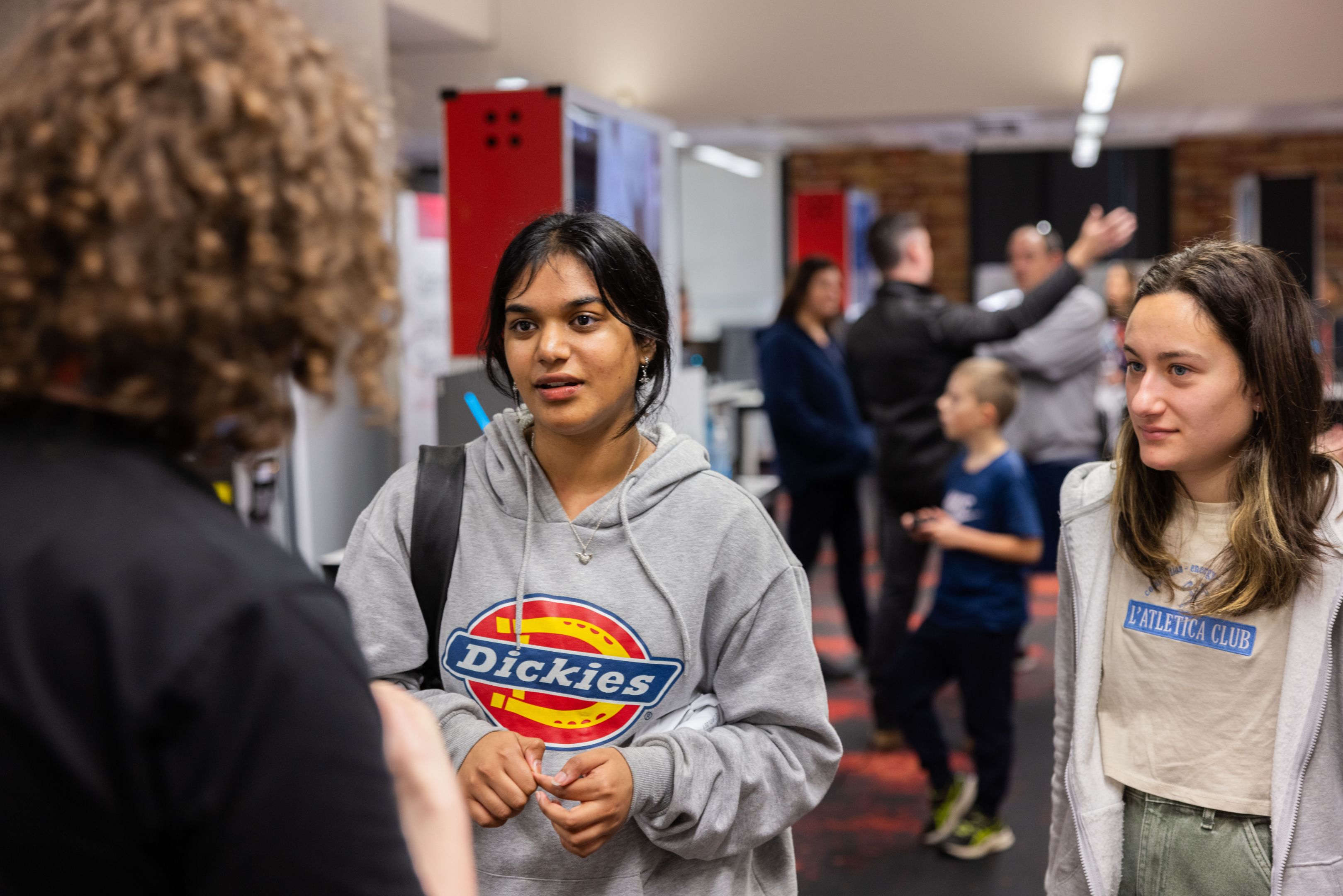 Two high school students speaking to a staff member at Swinburne Open Day.