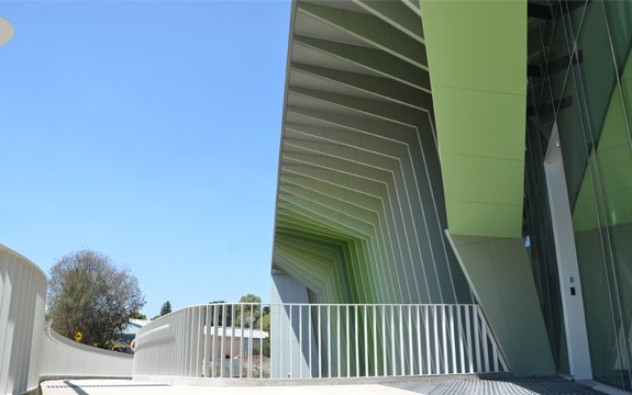 The entrance of a modern pale green building is shaded from the sun