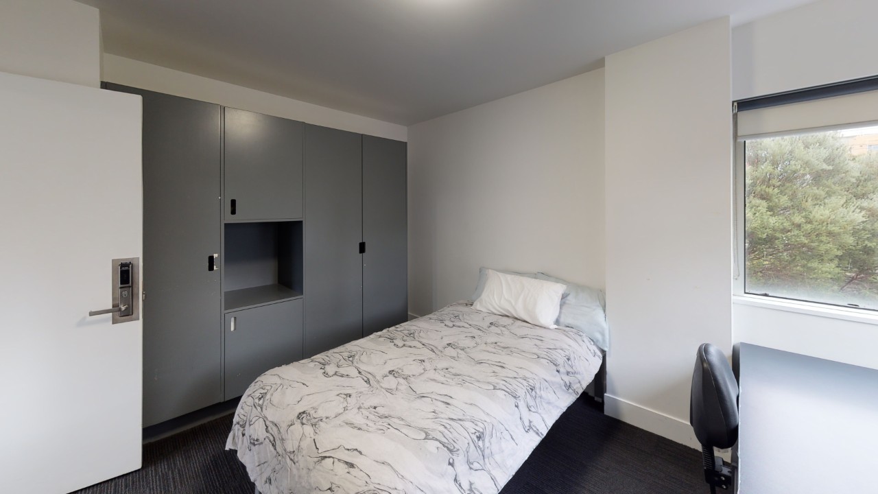 a small room with a bed, white doona cover and pillow