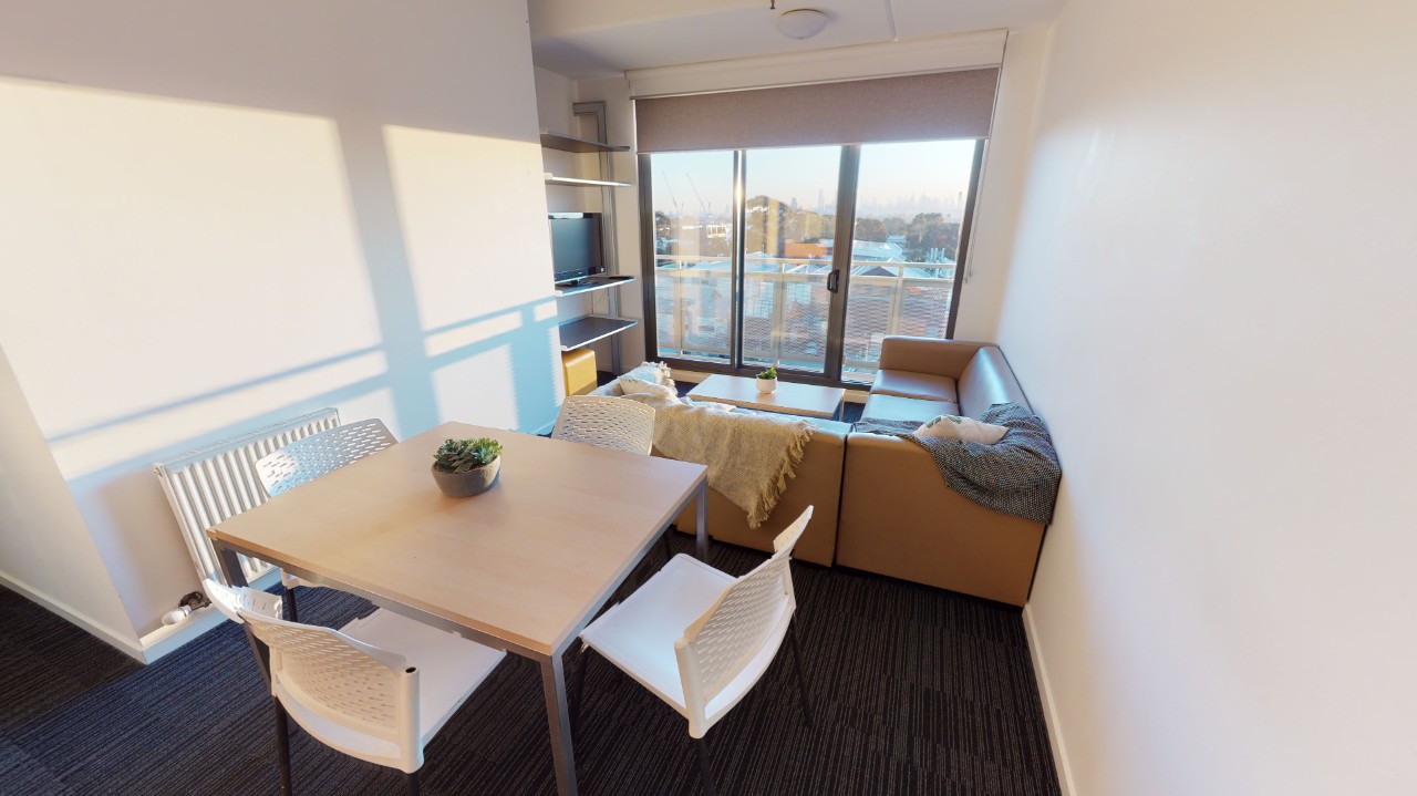 A shared living space with a small table, couch and TV