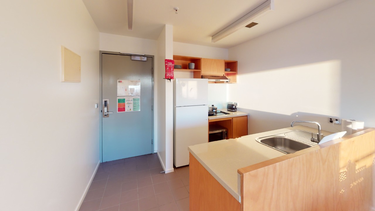 A kitchen area with fridge, sink and shelving