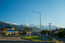 Scenic view of a road in a small town with snow capped mountains behind