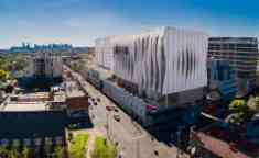 large square white building from high above city in the background blue sky