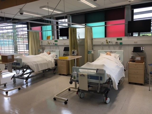 Health_Still Facility Photo_WS304_Simulation Lab Two full-body patient simulators lay in two hospital beds side by side. There is hospital equipment around the beds.