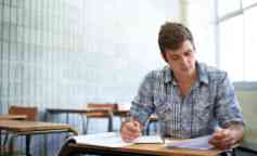 Shot of a male student sitting in a classroom going over his work.