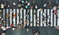 Aerial view of pedestrians walking on a busy pedestrian zebra crossing.