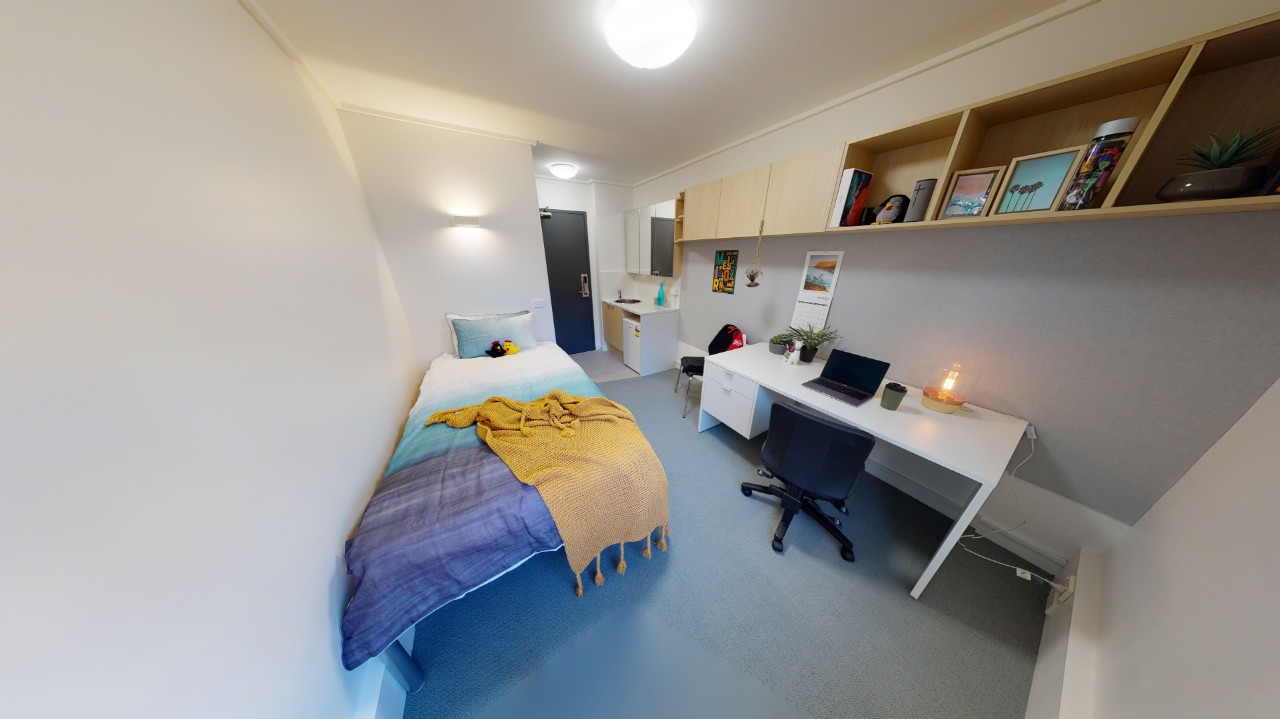 compact bedroom with single bed, desk, study chair and shelving