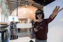 A woman wearing visual equipment reaches out to touch an object in augmented reality