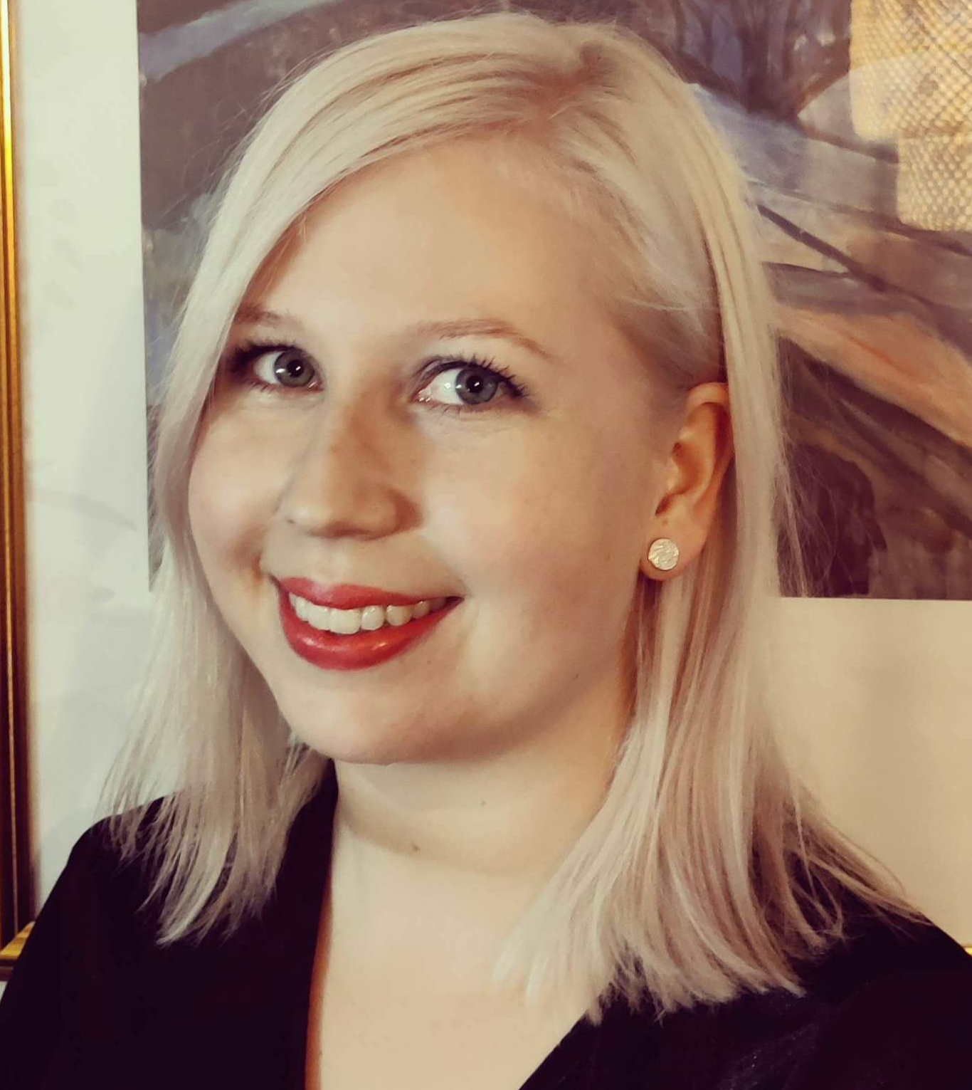 Headshot of woman with blond hair, wearing black top