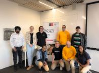 Nine people smile at the camera in front of a banner reading 'Swinburne Innovation Student