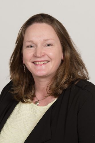 Headshot of Susan McVie wearing a yellow top and black blazer