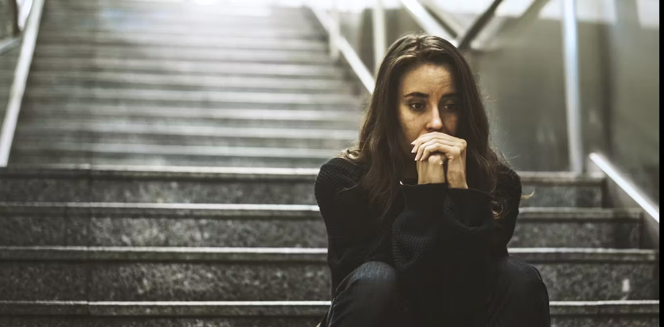 girl sitting at bottom of stairs looking worried