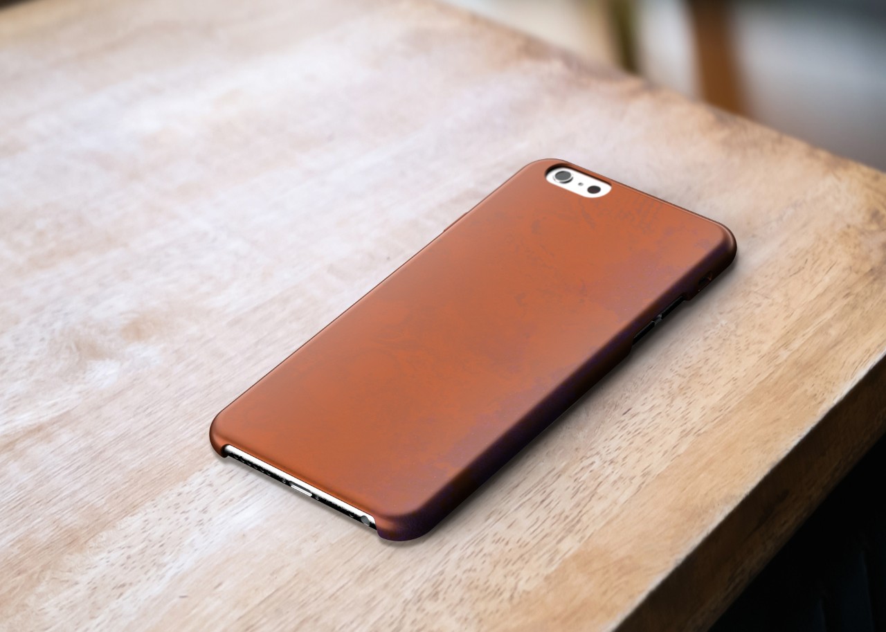 A mockup of a copper phone case sitting on a wooden table, moderate wear