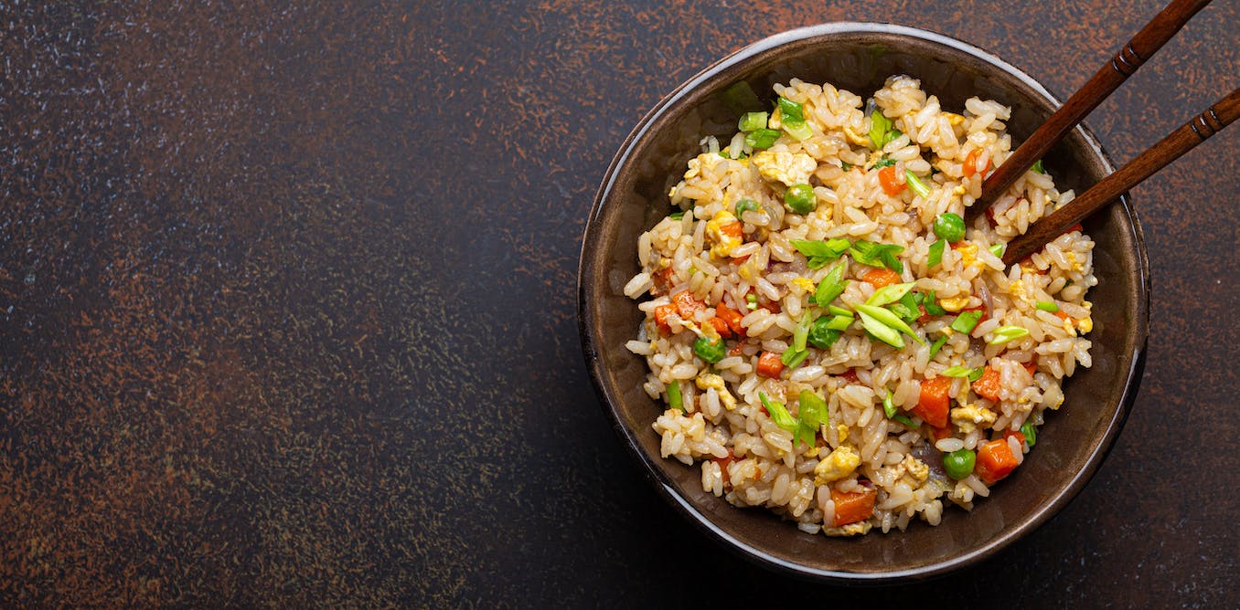 a bowl of fried rice with chop sticks on a table