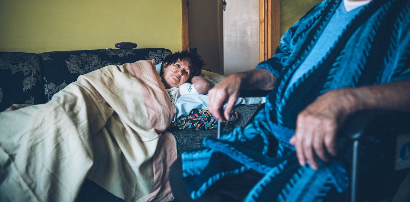 A woman sleeping on a couch and a man sitting in a chair