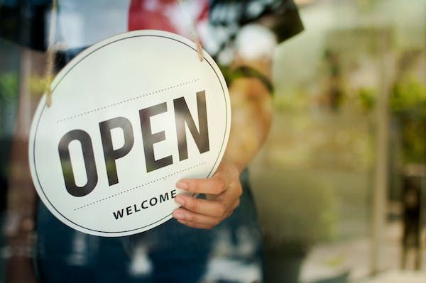 Open sign A person turning around the sign on the front of their business to read 'open welcome'