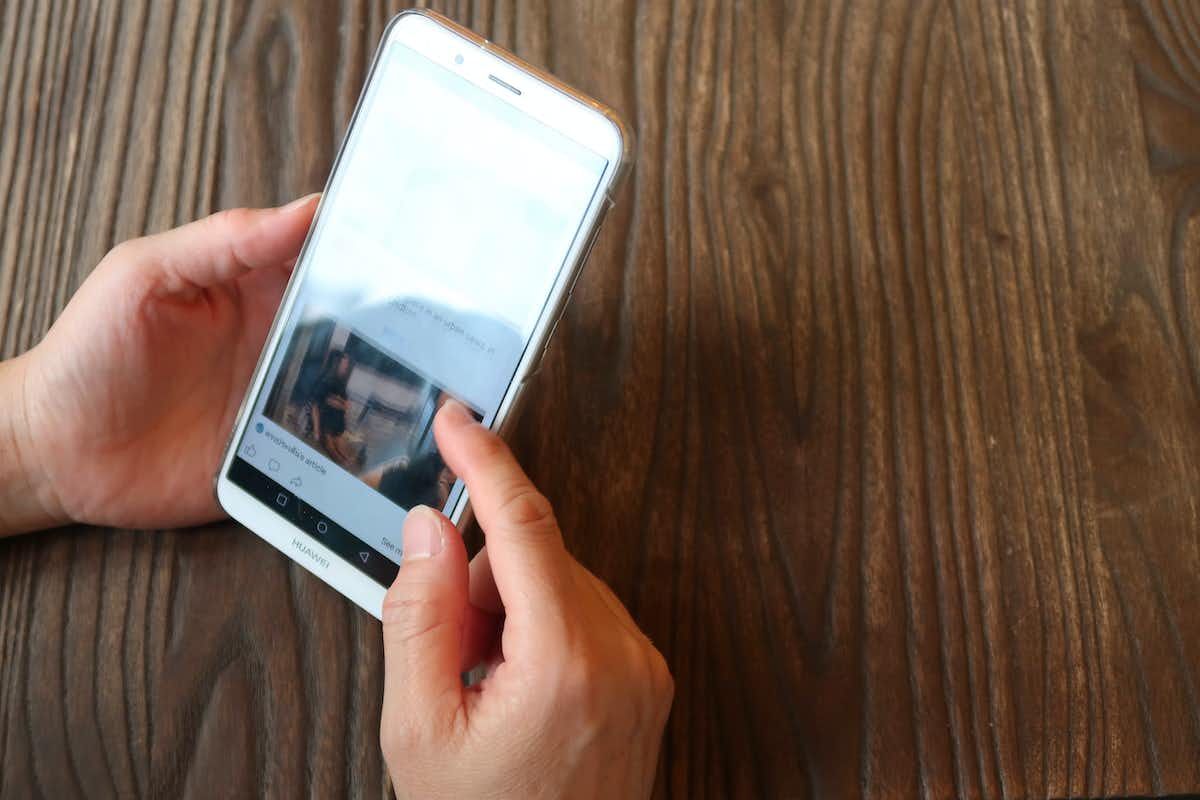 Scrolling through phone Someone holding a phone on a wooden table scrolling