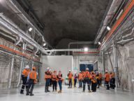A group of people in high-vis stand in a cavernous lab in a mine