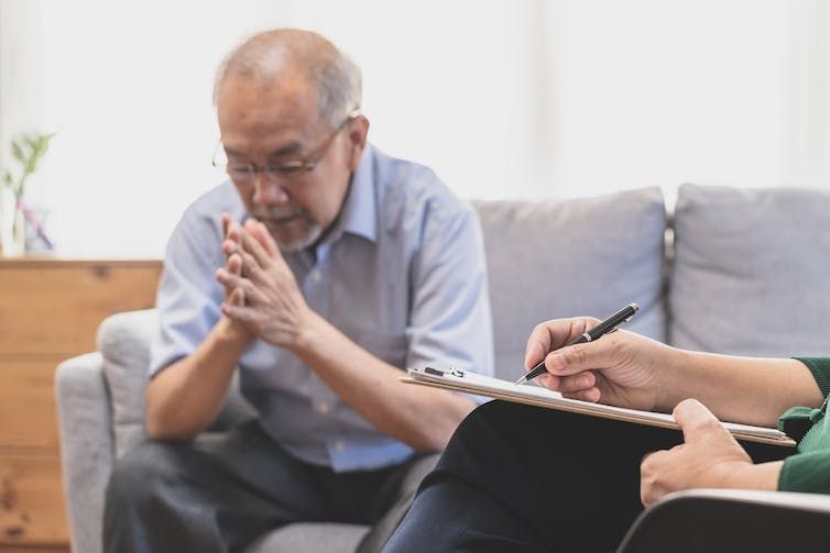 Talking to a therapist A man sitting on a couch talking with a therapist that is writing down notes on a clipboard