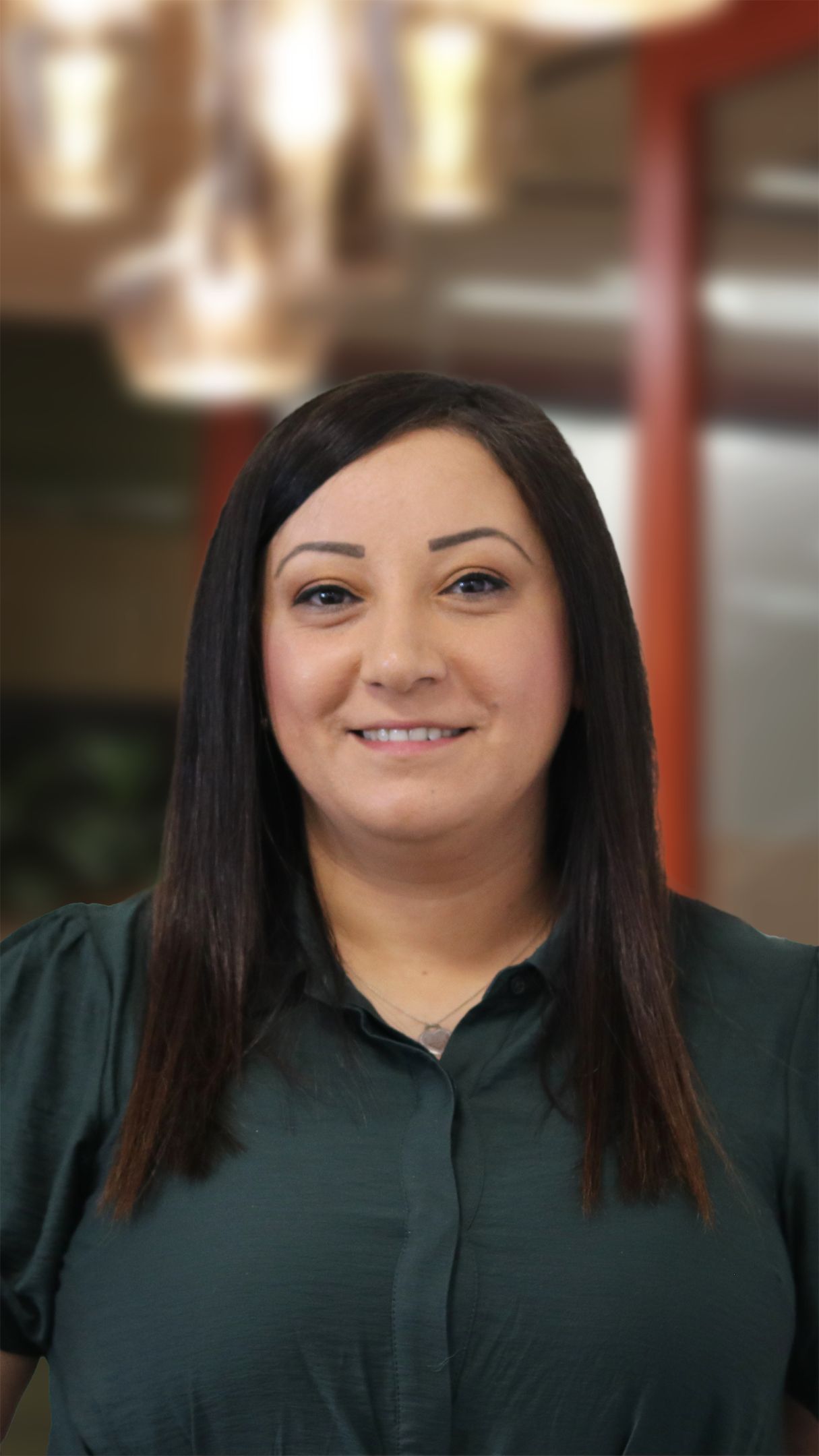 Woman with dark hair, wearing a green top smiling for the camera.