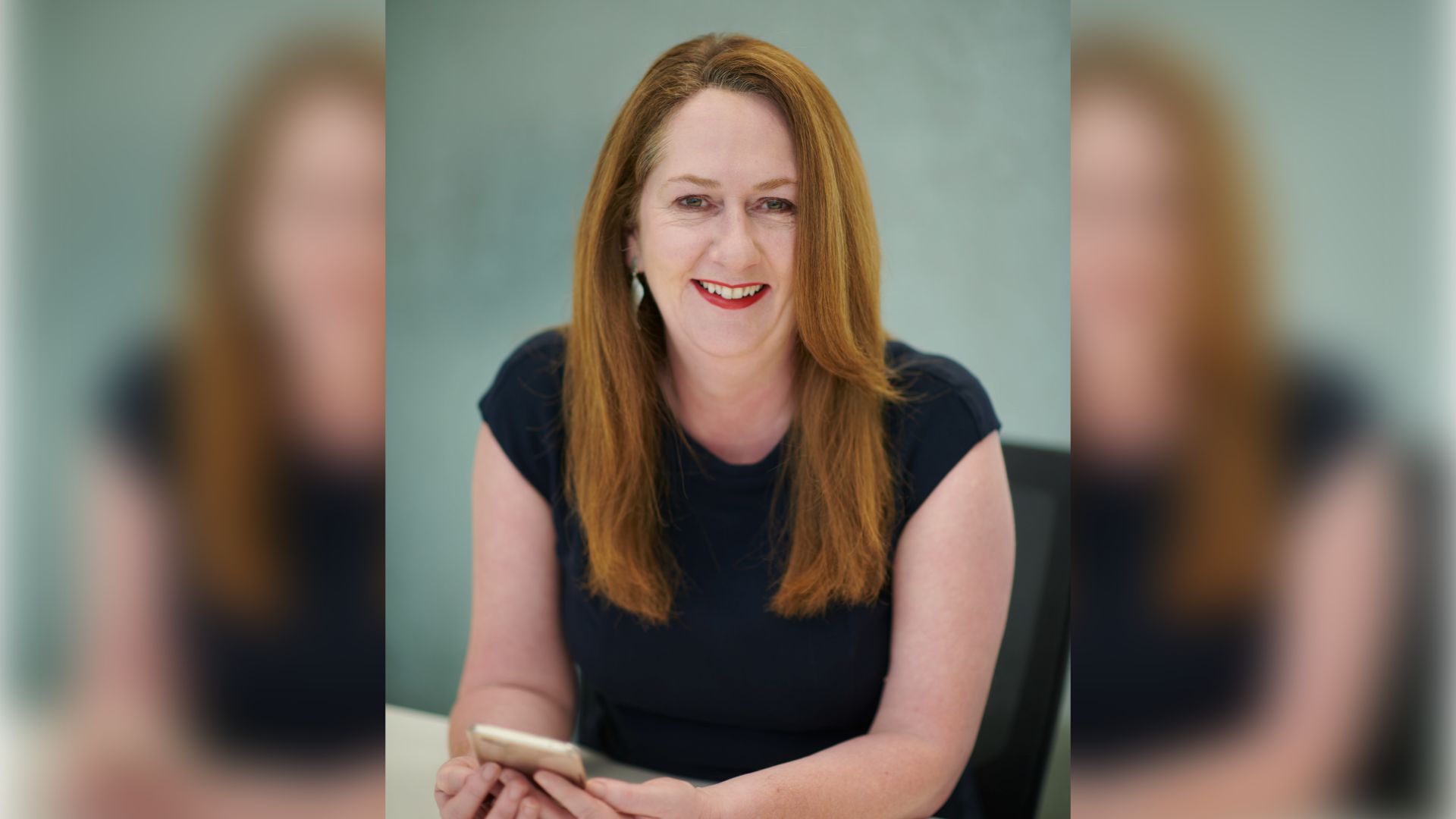 Swinburne alum and Associate Professor in Accounting at Swinburne, Dr Gráinne Oates is sitting at a desk smiling directly at the camera
