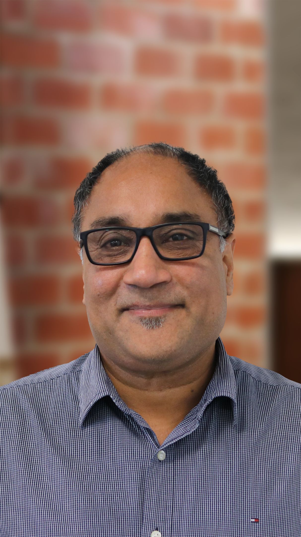 Close up of a man with glasses, smiling at the camera.