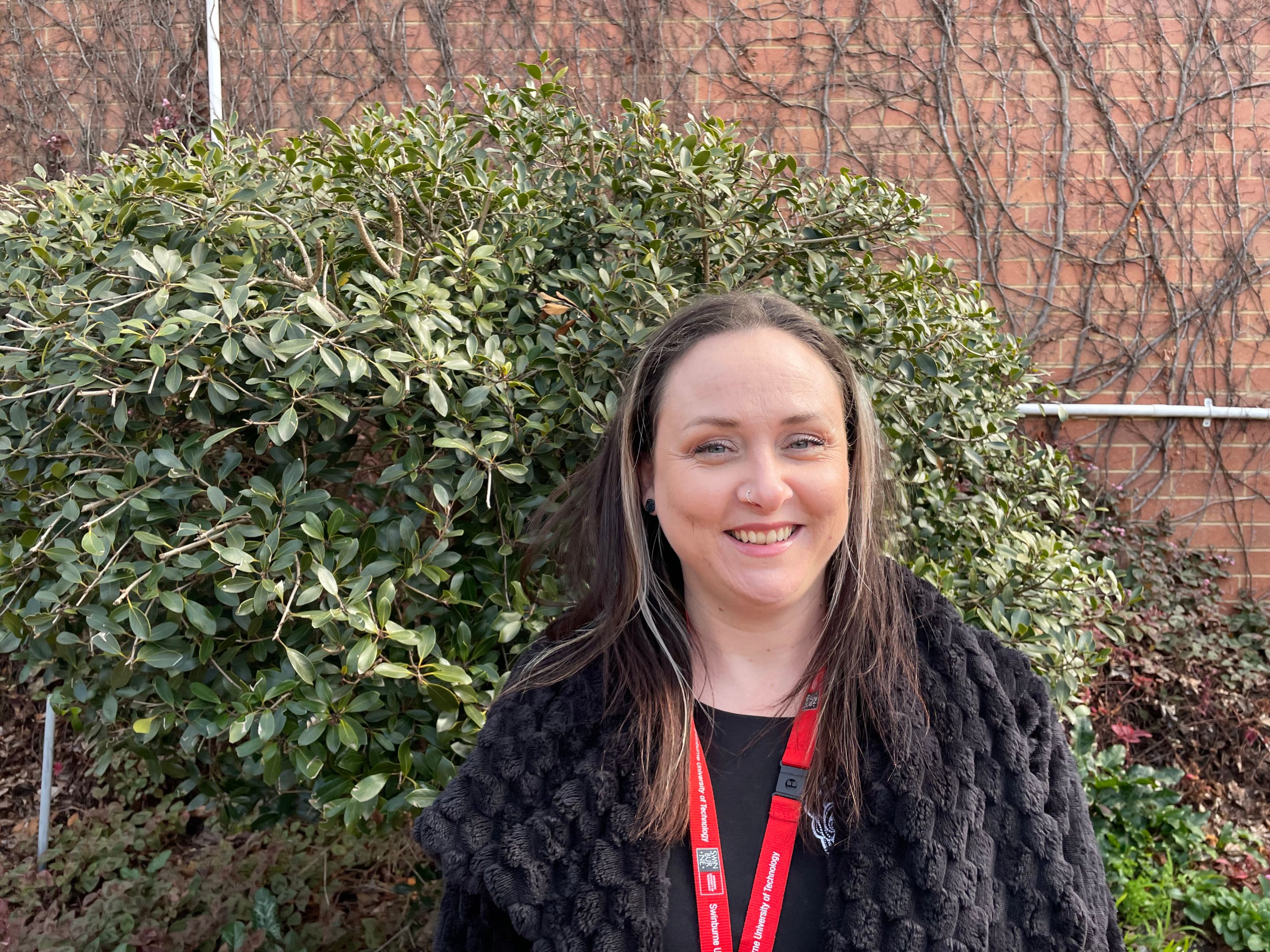 woman with hair down standing outside wearing swinburne lanyard