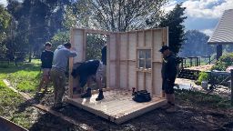 People assemble a cubby house in a backyard