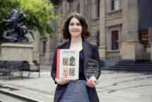 Woman standing outside state library holding book and award