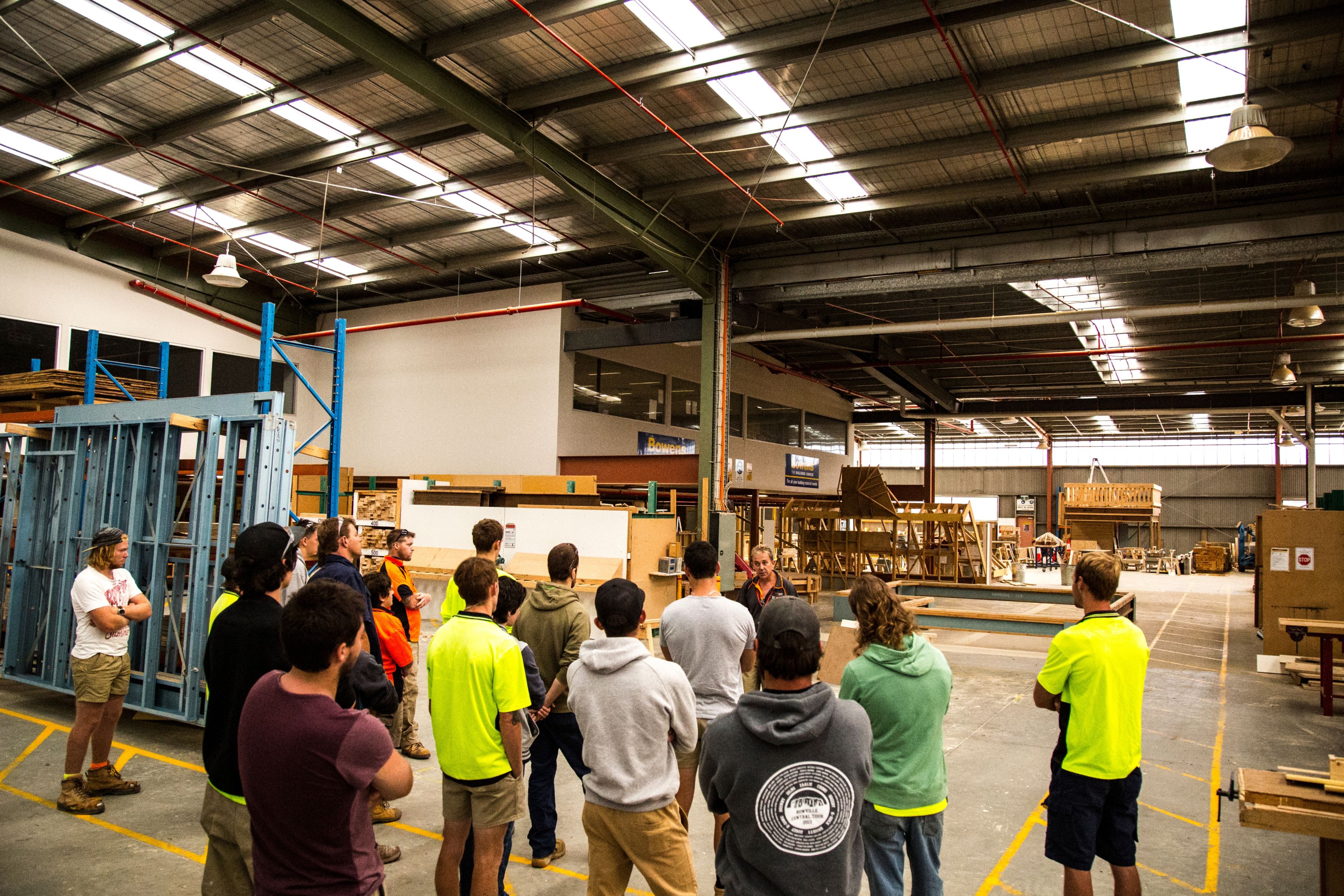 Group of young trade students listening to teacher in huge indoor room