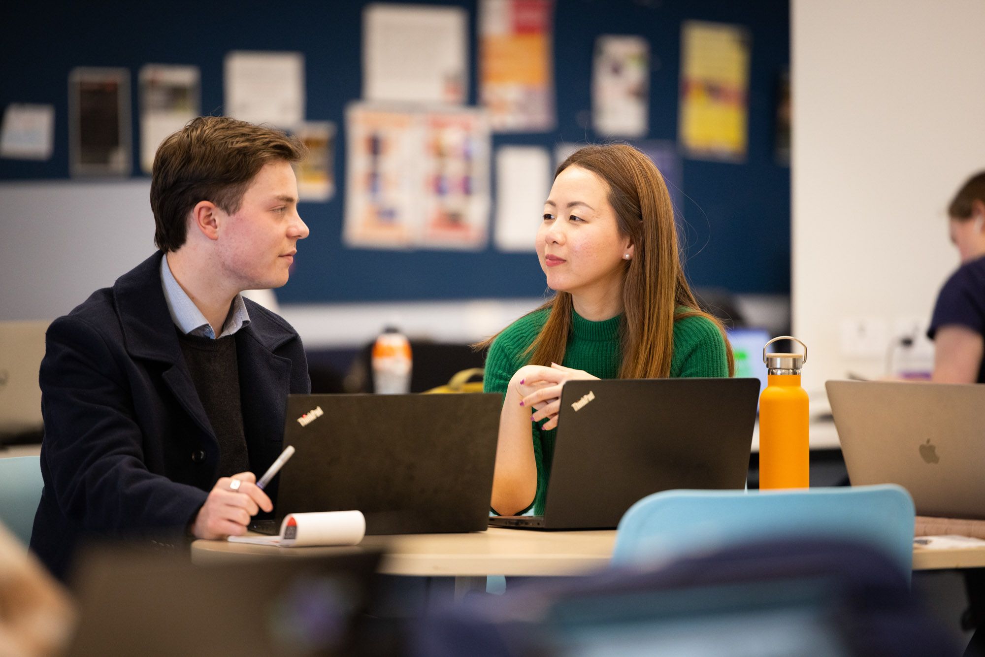 A woman in green is teaching a younger student