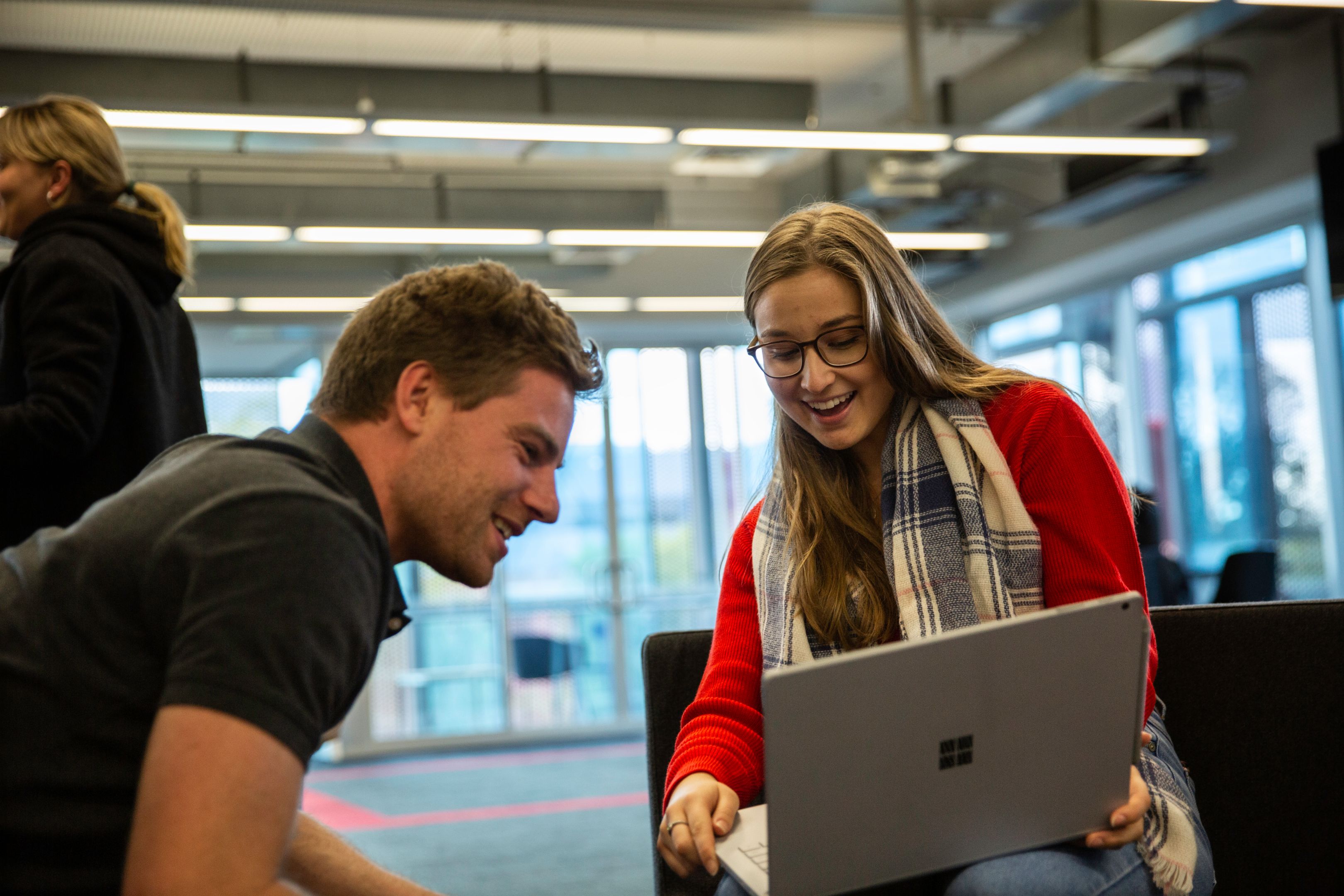 One male and one female student look at the work they've done on a laptop 