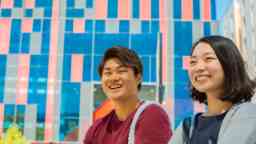 Two students, one man, one woman, smile broadly while sitting